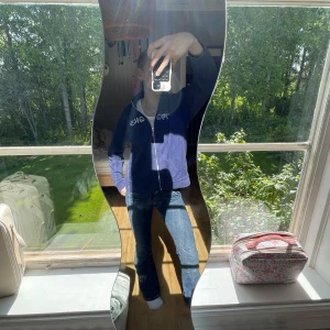 Blå zipjacka från Mooks med brodyr - Blå zipjacka från Mooks med broderade vita och gula tecken på bröstet. Jackan har hög krage, dragkedja framtill och är tillverkad i mjukt bomullsmaterial. Perfekt för en chill och avslappnad stil.