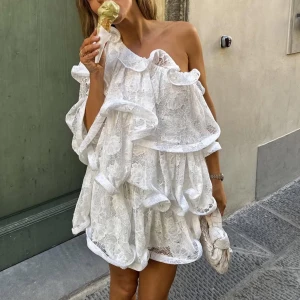 Vit miniklänning med spets & volanger, NA-KD - Lojsan Wallin  - Säljer denna magiska klänning från NA-KD - Lojsan Wallins kollektion! Så snygg med one-shoulder design. Perfekt som studentklänning/midsommarklänning. Helt helt slutsåld 🌸 ny med prislapp i orginalförpackning. Byter gärna mot en i stl 32 om någon vill byta, eller har en att sälja. 