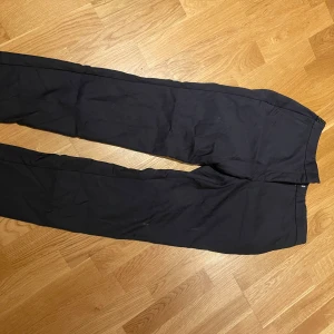Marinblå  kostymbyxor från Zara Basic - Säljer ett par marinblåa kostymbyxor från Zara Basic. Byxorna har raka ben och diskreta fickor framtill. Perfekta för en stilren look och passar till många olika tillfällen. 75:-
