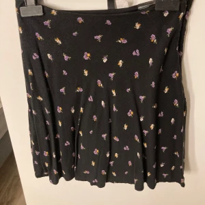 Svart blommig kjol från H&M Divided - Svart kortkjol från H&M Divided med små blommor i lila och gult. Kjolen har en lätt utställd form och är tillverkad i ett mjukt material som ger en skön känsla. Perfekt för dig som gillar en söt och enkel stil💗Säljer då det är fel storlek och inte passar eller kommer till användning. Använd max 2 gånger. Pris kan diskuteras💗