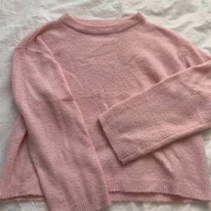 Rosa stickad tröja - Mysig rosa stickad tröja med rund hals och långa ärmar. Perfekt för kyliga dagar och ger en söt och avslappnad look. Passar bra till jeans eller kjol för en casual stil.