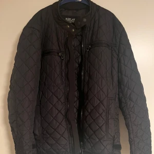 Svart quiltad jacka från Replay - Stilren quiltad jacka från Replay. Jackan har två bröstfickor med dragkedja och ett stilrent mönster. Perfekt för både kyligare dagar och sköna vår/höst dagar. 