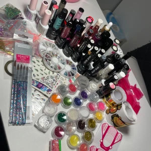 Stort set med nagelprodukter och glitter - Ett omfattande set med nagelprodukter inklusive 32 olika gellack 5 olika top coat  2 olika primers  9 olika baser  ( alla flaskor  har olika utgångsdatum, olika mycket använda. Men finns mycket kvar att ge och att använda)  37 olika glitter både i burk och zippåse  3 rondeller med stenar, 1 burk och 2 zip påsar  5 burkar med olika cromes 2 tejp 7 ark nagel vattenstickers 3 olika mallar  5 nya penslar  Och lite annat med följer 