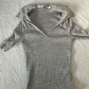 Beige ribbad tröja från Naked - Säljer en stilren beige ribbad tröja från H&M med v-ringning och trekvartsärmar. Perfekt för en chic och avslappnad look. Tröjan har en mjuk och bekväm passform som passar till många olika outfits.