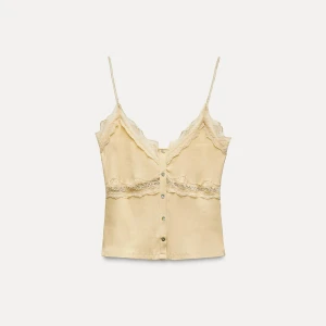 Beige ribbad linnetopp med spetsdetaljer - Säljer en söt beige ribbad linnetopp med smala axelband och spetsdetaljer. Toppen har knappar framtill och en v-ringad design. Perfekt för varma dagar eller som ett lager under en kavaj❤️