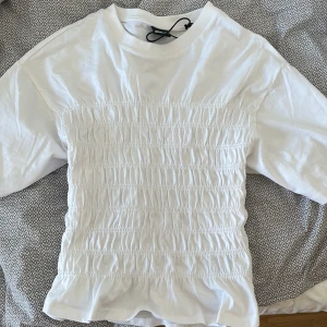 Vit ribbad topp med volanger - Jätte fin topp från Gina som aldrig använts, etikett kvar!!! Passar både S och Xs, säljer för att jag vill att den ska sitta tajtare då den på mig sitter lite pösigt i magen men de är bara mina preferenser 💖💖💖