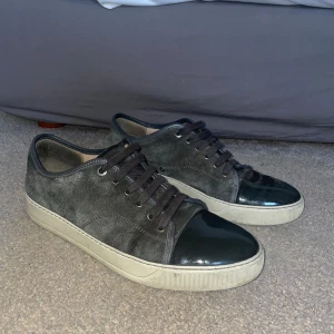 Lanvins - Snygga grå sneakers i mocka med svart, glansig rund tå och vita sulor. Skorna har snörning och en stilren design som passar perfekt för en avslappnad look. Lanvins