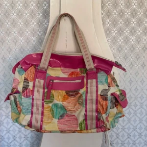 Färgglad axelväska från Roxy - Säljer en stor och rymlig axelväska från Roxy med färgglatt cirkelmönster och rosa detaljer. Väskan har dragkedja, flera fack och handtag i tyg. Perfekt för dig som vill ha en unik och lekfull accessoar.