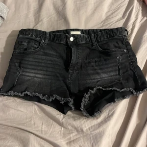 Svarta jeansshorts med fransar - Svarta jeansshorts med slitna detaljer och fransig kant nertill. Klassisk femficksmodell med knapp och dragkedja framtill. Perfekta för varma dagar och en avslappnad stil. Priset kan diskuteras 