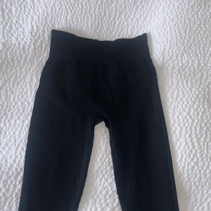 Svarta ribbade leggings från H&M Sport - Säljer ett par svarta ribbade leggings från H&M Sport i storlek S. De har hög midja och är tillverkade i ett stretchigt material som passar perfekt för träning eller en aktiv vardag.