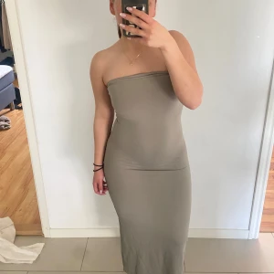 Grå axelbandslös långklänning - Säljer en stilren beige axelbandslös långklänning med tight passform. Superskönt material.