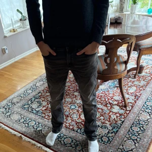 Hugo boss jeans - Säljer ett par grå jeans från Hugo med klassisk femficksdesign och röd logotypdetalj i linningen. Jeansen har en rak passform och är tillverkade i denim med lätt tvättad look. Perfekta för dig som gillar stilrena och moderna jeans. Knappt använda så gott som nyskick köpta på nk i julas. Nypris 1799