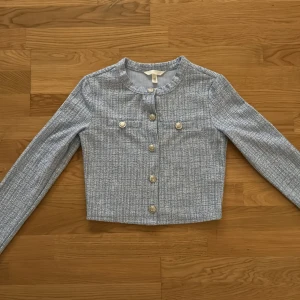 Ljusblå croppad kavaj med guldknappar - Storlek XS, Stilren. Använd 1 gång. Helt ny inga hål eller slitage alls. Som helt ny. 