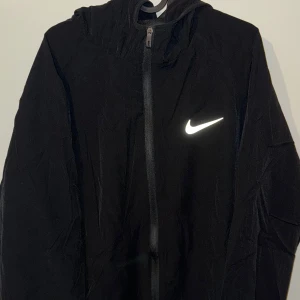 Windbreaker | Nike - Lätt och stilren windbreaker från Nike. Perfekt för både träning och vardag. Helt ny i originalskick, aldrig använd och med lappar kvar. Sportig och bekväm! (FÖRST TILL KVARN)