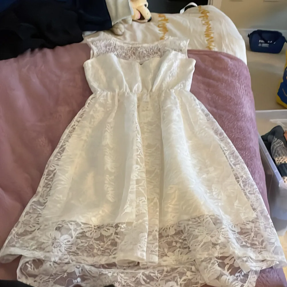 Säljer en elegant vit klänning från Dry Lake i storlek XXS.. Klänningen har ett vackert spetsöverdrag och är ärmlös med en rund halsringning. Perfekt för sommarens festligheter! 🌸Nyskick.. Mekot.
