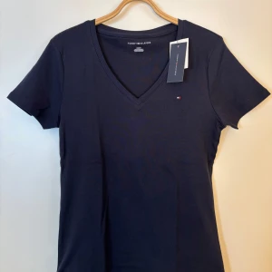 Tommy Hilfiger T-shirt  - Mörkblå T-shirt från Tommy hilfiger i storlek M. Köpt i USA och är aldrig använd, lapp sitter kvar💙