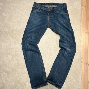 Nudie jeans - Averge Joe - Snygga blå jeans från Nudie Jeans i modellen Average Joe. Tillverkade av 100% ekologisk bomull med klassisk femficksdesign och orange sömmar på bakfickorna. Perfekta för en avslappnad stil.