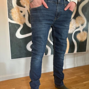 Levis jeans - Snygga blå jeans med en klassisk femficksdesign och knappgylf. De har en slim passform som ger en modern look. Perfekta för en stilren vardagsoutfit. 28/32