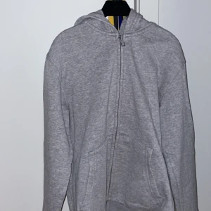 Grå hoodie från H&M - Säljer en grå hoodie från H&M i ekologisk bomull. Den har en dragkedja framtill och en praktisk huva. Perfekt för en avslappnad stil. Frakt tillkommer.