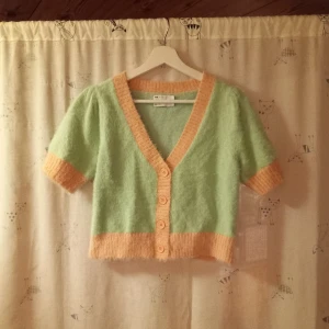 Grön och beige kofta från ASOS DESIGN - Säljer en söt och fluffig kofta i ljusgrönt med beige detaljer från ASOS DESIGN. Koftan har korta ärmar och knappar framtill. Perfekt för en mysig dag eller en avslappnad kväll. 🌿✨