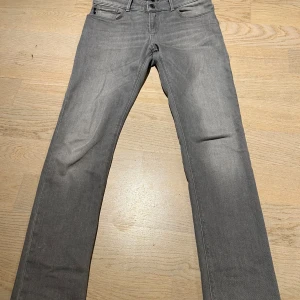 Grå jeans från Emporio Armani - Snygga grå jeans från Emporio Armani med en klassisk femficksdesign. De har en rak slim passform och är tillverkade i ett slitstarkt material. Perfekta för en stilren look.