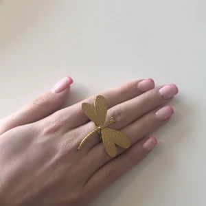 Guldfärgad ring med trollslända - Unik guldfärgad ring formad som en trollslända. Perfekt för att ge en naturinspirerad touch till din stil. Ringen har en detaljerad design med texturerade vingar.