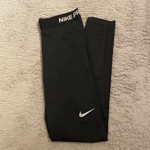 Svarta Nike Pro tights - Säljer ett par svarta Nike Pro tights med elastisk midja och vit logga. Använda men fortfarande bra skick. 🩷Obs Nike loggan på benet är slitet (bild 3)