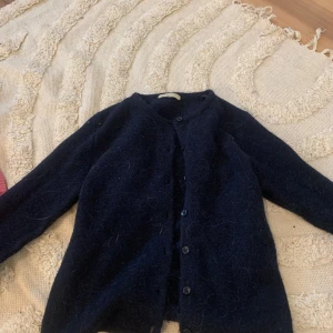 Svart kofta från Gina Tricot - Mysig svart kofta från Gina Tricot i premiumkvalitet. Koftan har långa ärmar och knappar framtill, perfekt för kyliga dagar. Enkel och stilren design som passar till det mesta.