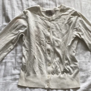 Vit kofta från H&M - Säljer en gullig vit kofta från H&M i storlek XS. Koftan har långa ärmar och knappar framtill. 