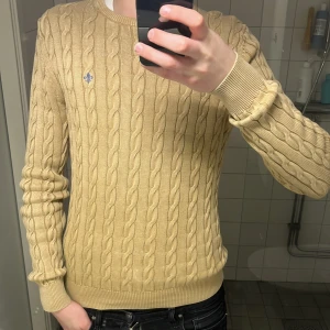 Beige stickad tröja från Morris - Säljer en stilren beige stickad tröja från Morris med kabelstickat mönster. 