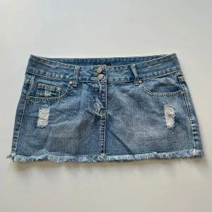 Lågmidjad kjol - Söt lågmidjad denim minikjol från Vert de Rage. Midjemått: 82 cm, 41 cm mätt platt. Längd: ca 28 cm. Dragkedjan är trasig, därav priset