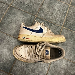 Nike Air Force 1 med blå Swoosh - Ett par hyfsat använda blå Nike air force 1, lite slitna i hälen men sånna skydd kostar 2kr på temu. Den gula nyansen på sulan är original ingen missfärgning eller annat!