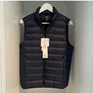 Svart dunväst från Uniqlo - Snygg och lätt svart dunväst från Uniqlo med dragkedja framtill. Helt ny med prislappen på. Nypris 599kr, mitt pris 349. Vid frågor är det bara att höra av sig!