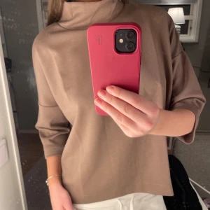 Beige polotröja - Säljer en stilren beige polotröja med trekvartsärm. Tröjan har en lös passform och är perfekt för en avslappnad look. Den mjuka färgen gör den lätt att matcha med olika outfits.