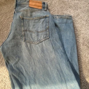 Jack & Jones Loose Chris jeans 29/32 - Ljusblå jeans från Jack & Jones i modellen Loose Chris. De har en loose passform med raka ben och klassisk femficksdesign. Jeansen är tillverkade i bomull och har snygga slitningar för en avslappnad vibe.