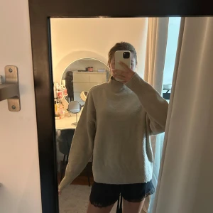 Beige stickad polotröja - Mysig beige stickad polotröja med avslappnad passform och långa ärmar. Tröjan har en hög krage och ribbade muddar vid ärmslut och nederkant. Perfekt för lager-på-lager under kyliga dagar.