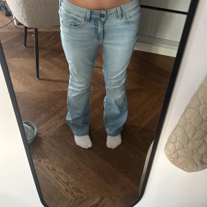 Ljusblå bootcut jeans Hollister - Säljer ett par ljusblå bootcut jeans från Hollister, modell Curvy Mid-Rise Boot/ funkar som lowwaist. Jeansen har klassisk femficksdesign, dragkedja och knapp framtill samt bälteshällor. Snygg passform med lite utsvängda ben och mjukt denimtyg. 800kr plus frakt
