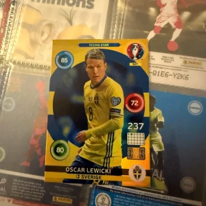 Oscar Lewicki (Rising star) - Ett fotbollskort som föreställer Oscar Lewicki med en sverigetröja, kortet är i väldigt fint skick. Det är ett perfekt tillskott till samlare eller personer som vill utöka sin kollektion med en rising star från Sverige. 