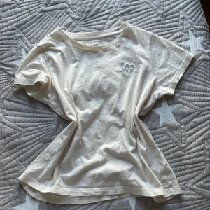 Beige t-shirt från Lee i bomull - Snygg beige t-shirt från Lee med liten logga broderad på bröstet. Klassisk rund halsringning och korta ärmar. Tillverkad i mjuk bomull som känns skön mot huden. Perfekt basic-plagg att ha i garderoben.