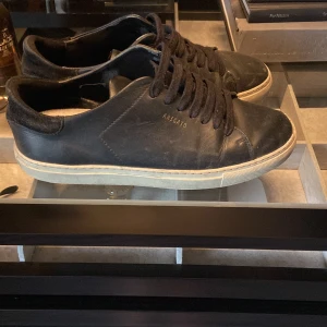 Svarta sneakers från Axel Arigato - Stilrena svarta sneakers från Axel Arigato med klassisk låg profil och vit sula. Skorna har snörning, rund tå och är tillverkade i skinn med detaljer i mocka vid hälen. Perfekta för en clean och urban look. Köpta på Care Of Carl för 2499, dustbag ingår! Storlek: 39, skick: 6/10, kan tänka mig att byta mot något annat! Pris kan annars diskuteras!