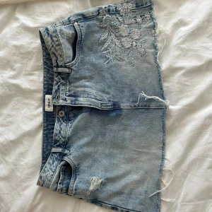 Ljusblå jeanskol med broderi från ONLY - Jättesöt jeanskjol från ONLY med fina blommiga broderier fram och bak. Storleken är 38 men jag tycker den passar bättre som S/36. Har använt ett fåtal gånger!🩷