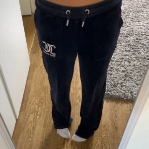 Mörkblå velourbyxor Juicy Couture - KOM MED PRISFÖRSLAG!!Mörkblå mjukisbyxor från Juicy Couture i mjuk velour med snörning i midjan och stora fickor fram och bak. Klassisk JC-logga i vitt på ena benet. Perfekta för en chill och trendig look. 
