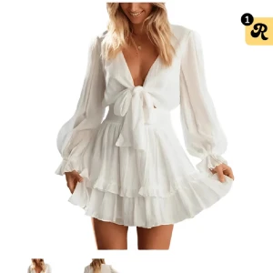 Vit omlottklänning Dressy - Superfin vit kortklänning med omlott och knyt i midjan, från Dressy. Klänningen har långa ärmar med volangdetaljer vid ärmslut och nederkant. Smockad midja ger en snygg passform och tyget är lätt och flowy, perfekt för sommarens alla tillfällen. Endast testad! Storlek S