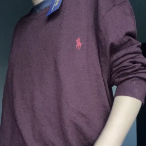 Vinröd tröja från Polo Ralph Lauren - Säljer en vinröd långärmad tröja från Polo Ralph Lauren i storlek XL. Tröjan har rund halsringning och den klassiska broderade loggan på bröstet. Perfekt för dig som gillar stilrena och tidlösa plagg. Helt oanvänd behöver bara strykas. Det är en tunn tjocktröja!