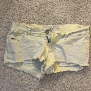 Låga Ljusgula jeansshorts från Hollister - Snygga ljusgula jeansshorts från Hollister med fransig kant och klassisk femficksdesign. Shortsen har låg midja, bälteshällor och dragkedja med knapp. Perfekta för varma sommardagar och en avslappnad stil.