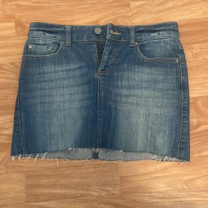 Jeanskjol - Snygg blå jeanskjol från Bondelid med rå kant nertill och klassiska fem fickor. Kjolen har bälteshällor, knapp och dragkedja framtill samt bakfickor. Perfekt för dig som gillar en avslappnad och trendig stil. Midjemått 36 cm rakt över