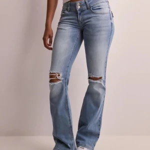 Ljusblå bootcut jeans med hål  - Snygga low waist ljusblå jeans med bootcut passform och slitna detaljer över knäna. Jeansen är något slitna längst ner på byxbenen, säljer då dom är för stora för mig.❤️ nypris 699kr.  Byxorna är köpta i storlek 34 men är stora i storleken, passar bättre som storlek 38! Tvärs över midjan är måttet 37 cm och innerbensländen är 83 cm❤️