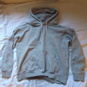 Grå basic hoodie - En basic grå hoodie med huva och vita snören. Bra att ha om det blir kallt, passar till vad som helst. Säljer eftersom den blivit för liten för mig. 