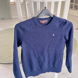Merino tröja Morris - Klassisk stickad tröja från Morris i 100% merino ull. Marinblå med rund hals och diskret broderad logga på bröstet. Perfekt för dig som gillar stilrena och tidlösa plagg med en snygg passform och mjuk känsla. Passar om man är runt 165.