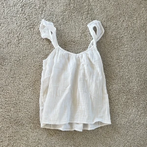 Vit linnetopp från MNG i XS - Superfin vit linnetopp från MNG i storlek XS. Toppen har tunna axelband, lätt rynkad struktur och är tillverkad i ett luftigt bomullstyg. 